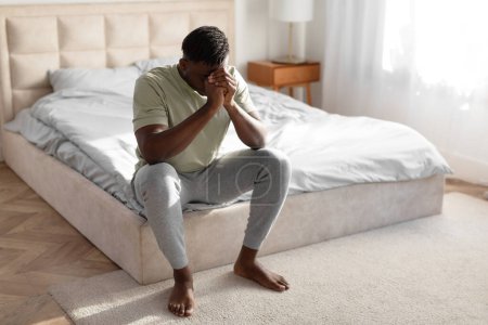 Photo for Male Depression Problem. Desperate African American Man Covering Face Experiencing Mental Health Issues, Feeling Lonely Sitting On Bed In Home Bedroom Interior. Concept Of Frustration. Copy Space - Royalty Free Image