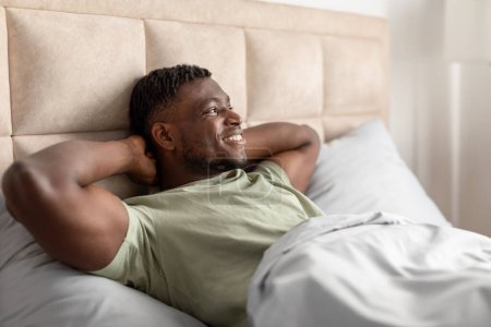 Photo for Good Morning. Happy Black Guy Lying Awake Relaxing In The Morning In Comfortable Bed Indoors, Holding Hands Behind Head While Enjoying His Rest On Weekend. Recreation Routine Concept - Royalty Free Image