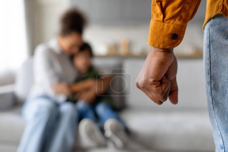Photo for In focus, fathers clenched fist signifies tension while mother and child boy share comforting embrace in the softly blurred background, family problems - Royalty Free Image