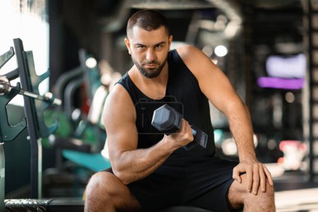 Photo for Young Muscular Man Doing Exercises With Dumbbell In Modern Gym, Handsome Athletic Male Making Seated Biceps Curl, Enjoying Workout With Heavy Weights For Muscle Strength, Free Space - Royalty Free Image