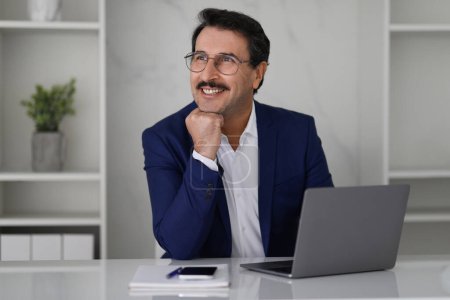 Photo for Smiling pensive caucasian mature businessman in suit at table with computer laptop, think, look at free space in modern office interior. Work, business, boss device, create idea for startup - Royalty Free Image