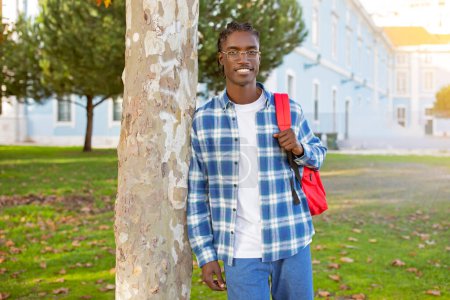 Téléchargez les photos : Joyeux élève. Toothy Afro-Américain avec sac à dos rouge se tient à l'extérieur, regardant la caméra avec un sourire confiant, dépeignant le succès éducatif et l'ambition. Espace vide pour le texte - en image libre de droit