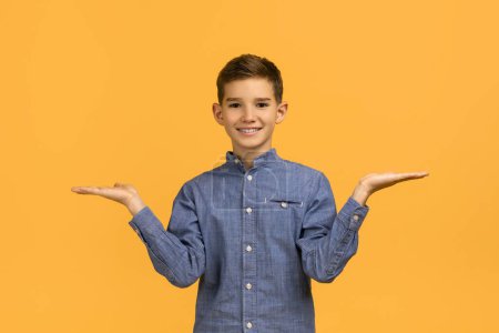 Photo for Make Choice. Cheerful teen boy making scales with his empty palms, smiling happy teenage male kid comparing options while standing isolated over yellow studio background, copy space - Royalty Free Image