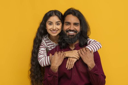 Téléchargez les photos : Gros plan portrait de joyeux jeune couple indien embrassant et souriant à la caméra. Heureux millénaire homme et femme de l'Est posant isolé sur fond de studio jaune. Famille, mariage, relations - en image libre de droit