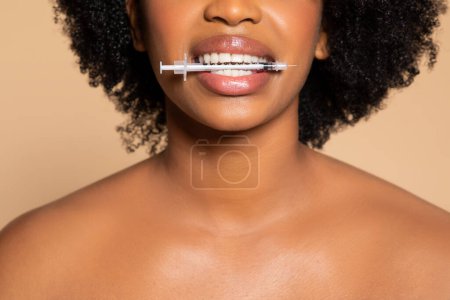 Foto de Primer plano detallado de la mujer que recibe la inyección de belleza cosmética en sus labios, destacando los tratamientos modernos de cuidado de la piel contra el fondo beige - Imagen libre de derechos