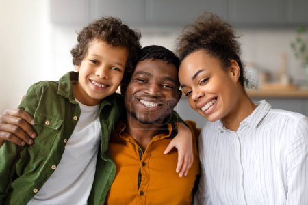 Foto de Familia negra radiante de tres compartidos abrazo cercano y afectuoso, con rostros sonrientes y alegría evidente, creando retrato de felicidad y unidad - Imagen libre de derechos
