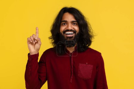 Téléchargez les photos : Excité inspiré poilu jeune homme indien lever le doigt et sourire, ont idée créative, grande solution, posant isolé sur fond de studio jaune. Inspiration, créativité, innovation - en image libre de droit