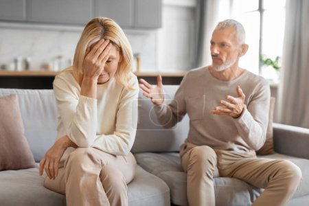 Photo for Domestic violence, abuse in marriage. Angry elderly grey-haired man yelling and gesturing at his tired upset wife, senior couple sitting on couch at home, have fight - Royalty Free Image