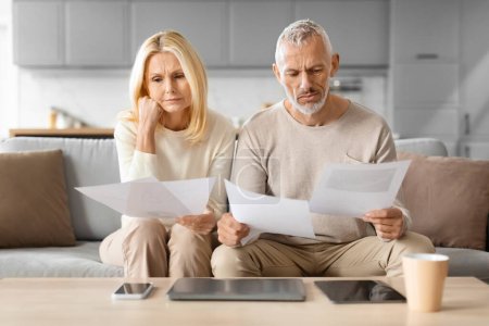 Photo for Worried Senior Spouses Reading Papers And Bills Sitting In Front Of Laptop Computer Counting Expenses At Home. Financial Paperwork And Household, Retirement Lifestyle Concept - Royalty Free Image