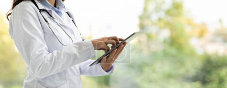 Photo for Cropped of woman doctor in white coat work on tablet, posing at clinic, web-banner, copy space. Modern device for remote online consultation, new normal with medical application - Royalty Free Image