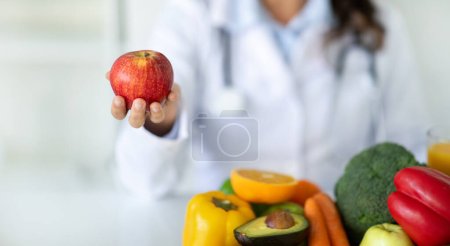 Foto de Escritorio nutricionista con frutas y verduras saludables. Dietista trabajando en plan de dieta, mostrando manzana roja orgánica. Pérdida de peso y el concepto de nutrición correcta, banner web, recortado - Imagen libre de derechos
