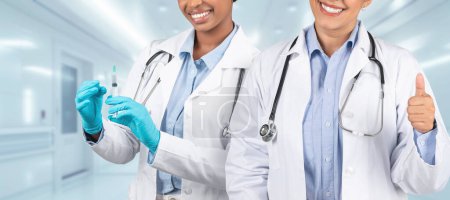 Photo for Two happy medical professionals in white coats, one preparing a syringe and the other giving a thumbs up, symbolize excellent healthcare and patient support in clinic, panorama - Royalty Free Image