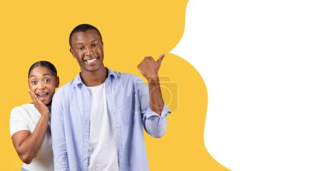 Photo for Joyful black couple pointing thumb aside at empty text bubble, advertising wow offer, demonstrating blank mockup place together against yellow studio backdrop, panorama, collage - Royalty Free Image