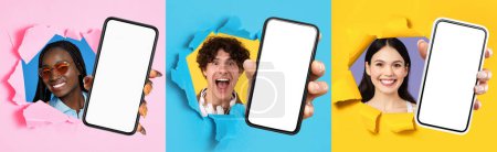 Photo for Three cheerful multiethnic people popping through colorful paper tears, each holding a smartphone with a blank screen, on a bright split background, panorama. App, device recommendation - Royalty Free Image