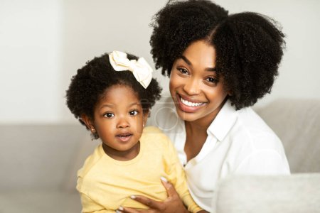 Photo for Motherhood. Portrait of happy cute african american young beautiful mother and little daughter toddler bonding at home, enjoying time together. Black mom cuddling with her sweet child girl - Royalty Free Image