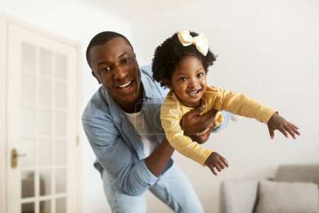 Photo for Handsome young african american father have fun with his daughter cute little girl at home. Happy black dad lifting up his beautiful toddler child, enjoying time together. Family, affectionate - Royalty Free Image