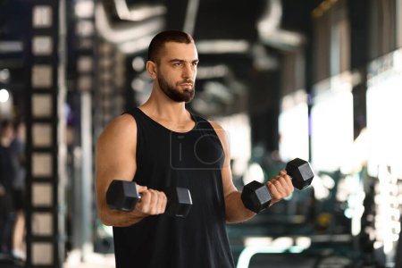 Photo for Portrait Of Motivated Male Athlete Exercising With Dumbbells At Fitness Club, Muscular Young Man Using Heavy Sport Equipment For Biceps Workout At Gym, Sporty Guy Enjoying Bodybuilding - Royalty Free Image