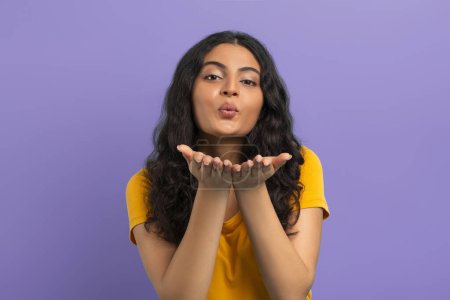 Photo for Cute pretty young indian woman sending fly kiss at camera, expressing her feelings, showing love and affection, posing isolated on purple studio background - Royalty Free Image