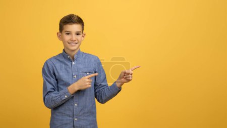 Photo for Nice Offer. Happy Smiling Teen Boy Pointing Aside At Copy Space With Two Hands, Cheerful Male Teenager Demonstrating Free Place For Advertisement While Standing On Yellow Background, Panorama - Royalty Free Image