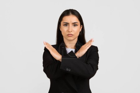 Téléchargez les photos : Femme d'affaires professionnelle en costume noir faisant fermement un geste négatif, croisant les bras pour indiquer un refus strict ou fixant des limites dans le contexte des affaires - en image libre de droit