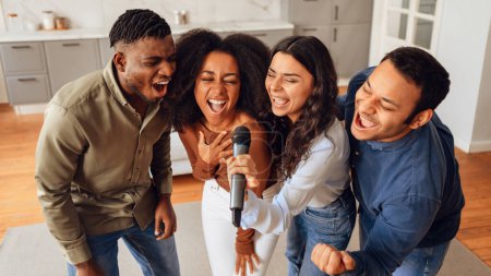 Photo for Karaoke party. Diverse friends gathering in home living room, celebrating with joyful singing and relaxation, creating lively atmosphere of friendship and youthful joy on weekend. Panorama - Royalty Free Image