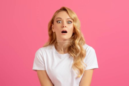 Téléchargez les photos : Femme blonde millénaire choquée ouvrant la bouche avec une expression étonnante, réagissant à des nouvelles inattendues, posant sur fond de studio rose, se sentant effrayée ou dépassée en regardant la caméra - en image libre de droit