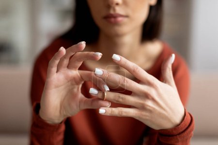 Photo for Closeup shot of upset young woman taking off wedding ring at home, depressed millennial female suffering relationship problems, marital crisis or breakup, getting ready for divorse, cropped - Royalty Free Image
