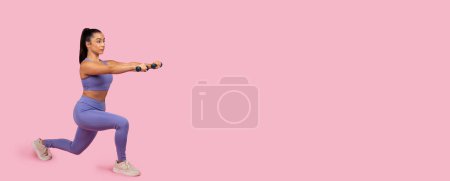 Téléchargez les photos : Passionné de fitness concentré tient position de fente avec haltères, mettant en valeur la force et l'équilibre dans la tenue d'exercice violet sur fond rose, panorama, espace de copie - en image libre de droit