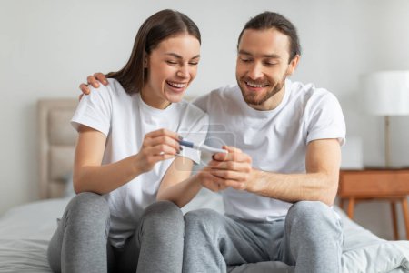 Foto de Joven pareja europea llena de alegría comparte momento de felicidad mientras miran la prueba de embarazo positiva, simbolizando nuevos comienzos y alegría compartida - Imagen libre de derechos
