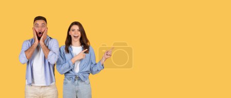 Photo for Shocked young man with open-mouthed expression and joyful woman pointing to the side at free space, both standing against vibrant yellow background, panorama - Royalty Free Image