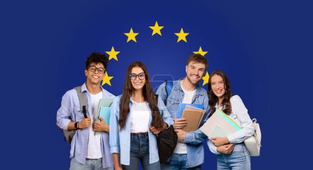 Téléchargez les photos : Groupe millénaire joyeux de quatre amis collégiaux avec des livres debout devant un drapeau de l'Union européenne, représentant des possibilités d'études internationales ou programme Erasmus, panorama - en image libre de droit