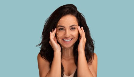 Konzept zur Gesichtsverjüngung. Lächelnde attraktive junge brünette Frau mit Gesichtsstraffungslinien, die ihr Gesicht auf blauem Hintergrund massieren, Konzept der kosmetischen Chirurgie und Anti-Aging-Behandlungen