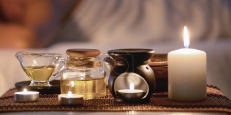 Photo for Aroma massage concept. Lady relaxing in spa with composition of candles and oils on foreground - Royalty Free Image