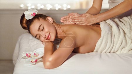 Téléchargez les photos : Soins de la peau. Femme profitant de massage relaxant du dos dans le centre de spa de cosmétologie - en image libre de droit