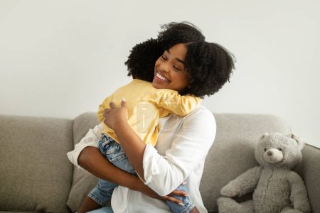 Photo for Mother care. Portrait of beautiful african american woman hugging infant child, home interior. Cheerful young black mom embracing with her little daughter, copy space. Parenthood concept - Royalty Free Image
