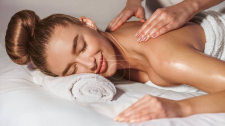 Foto de Relajación total. Mujer volviendo masaje en el centro de spa con orquídeas cerca - Imagen libre de derechos