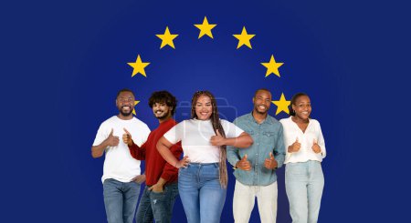 Foto de Cinco felices millennials de diversas etnias dando pulgares hacia arriba, vistiendo ropa casual en un contexto con estrellas de la Unión Europea, señalando la aprobación y la unidad - Imagen libre de derechos