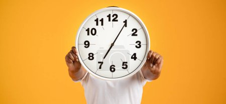 Photo for Unrecognizable black lady poses with a clock covering her head against orange studio background, emphasizing concept of punctuality, deadline and time management. Panorama - Royalty Free Image