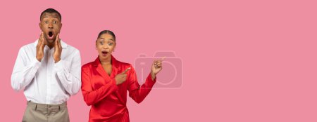 Photo for Startled young black man with hands on cheeks and astonished young woman pointing aside at free space, both showing exaggerated expressions on broad pink background - Royalty Free Image