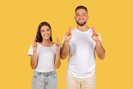 Photo for Concerned european young couple in white t-shirts standing back to back with worried expressions, deep in thought and contemplation, against a plain yellow studio background - Royalty Free Image