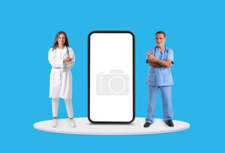 Medizinisches Team, reife Ärztin und Krankenschwester, präsentiert riesigen Smartphone-Bildschirm, ideal für Gesundheits-Apps vor klarem blauen Hintergrund