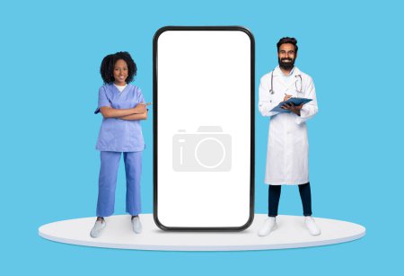 Téléchargez les photos : Infirmière et médecin confiants avec presse-papiers à côté d'un énorme écran vertical pour smartphone, idéal pour les promotions d'applications de soins de santé, sur fond bleu, maquette - en image libre de droit