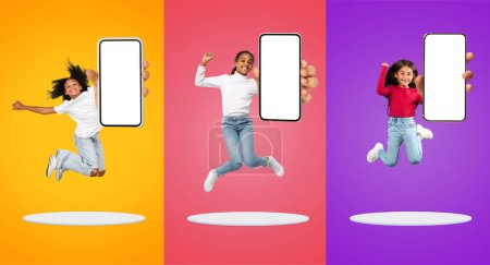 Photo for App For Kids. Cheerful Little Girls With Blank Smartphones In Hands Jumping Above Platforms Over Colorful Backgrounds, Happy Multiethnic Kids Recommending Mobile Application, Collage, Mockup - Royalty Free Image