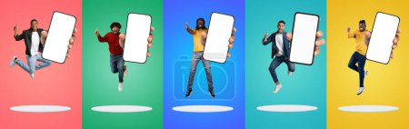 Téléchargez les photos : Cool App. Groupe d'hommes multiethniques heureux démontrant de grands smartphones vides avec écran blanc, les hommes gais avec des téléphones cellulaires vides sautant au-dessus des plates-formes sur des milieux de studio colorés, Mockup - en image libre de droit