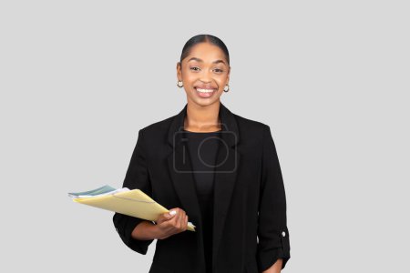 Photo for Positive millennial black lady secretary, manager in formal suit documents, clipboard, isolated on gray studio background. Business, work and study, ad and offer, startup - Royalty Free Image