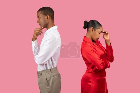 Photo for Reflective black man and contemplative woman, both standing back-to-back, looking down in deep thought, isolated against pink background, side view - Royalty Free Image