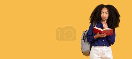 Photo for Contemplative young black woman with backpack, holding red book and pen, looking thoughtful against yellow background, contemplating notes, panorama with free space - Royalty Free Image