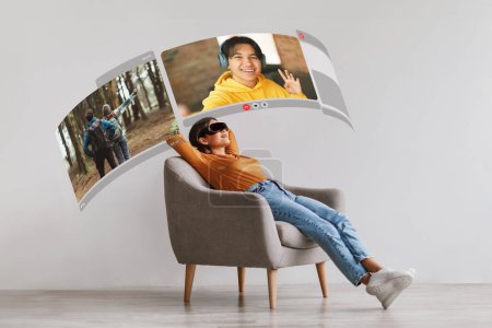 Manera moderna de conectar: mujer asiática joven que usa equipo VR para experimentar una conversación de video realista con su novio en casa, descansando en un sillón