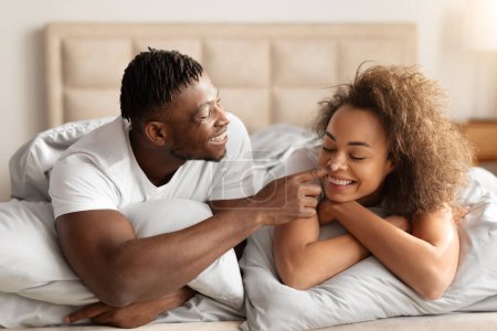 Photo for Romantic Morning. Loving Black Young Man Touching Wifes Nose Lying In Bed, Couple Flirting Enjoying Morning Romance Together In Their Modern Cozy Bedroom At Home. Happy Marriage - Royalty Free Image