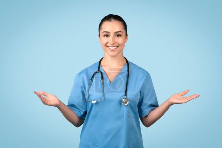 Enfermera alegre en matorrales azules con estetoscopio de pie con las palmas abiertas, lista para ayudar o presentar opciones de atención médica con un comportamiento amigable